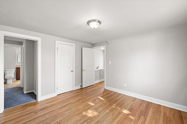 unfurnished bedroom with baseboards, connected bathroom, and light wood-style floors