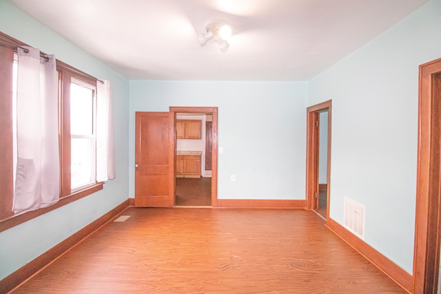 spare room featuring light wood finished floors, visible vents, and baseboards