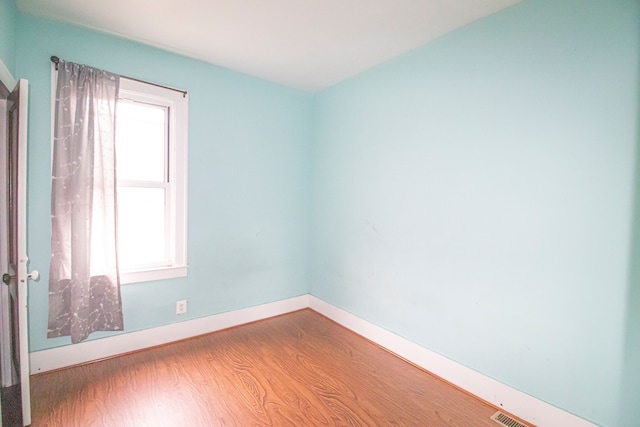 spare room featuring visible vents, baseboards, and wood finished floors