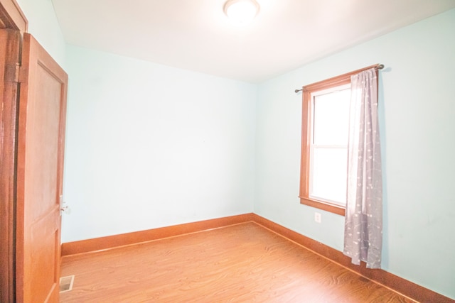 spare room featuring wood finished floors, visible vents, and baseboards