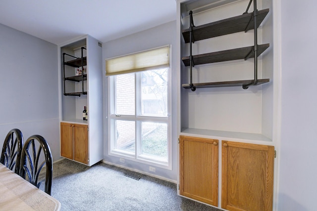 unfurnished dining area with carpet floors, visible vents, and baseboards