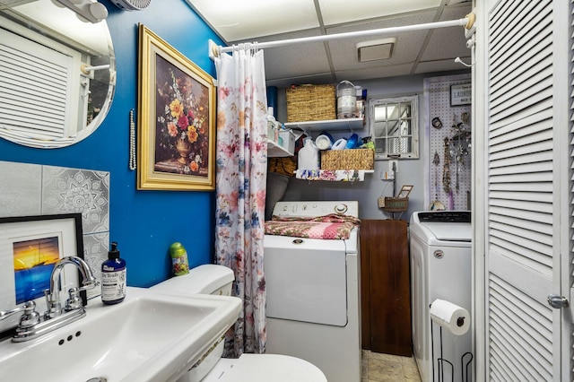 bathroom with a paneled ceiling, a closet, a sink, and washer / dryer