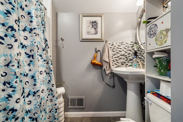 bathroom featuring tasteful backsplash, visible vents, toilet, wood finished floors, and baseboards