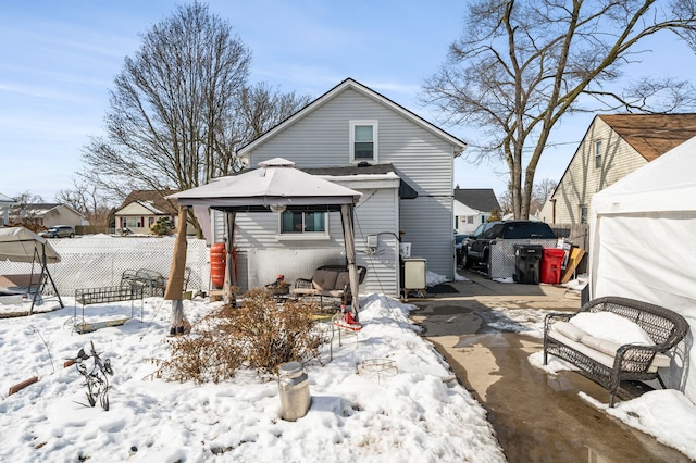 snow covered rear of property featuring fence and a gazebo