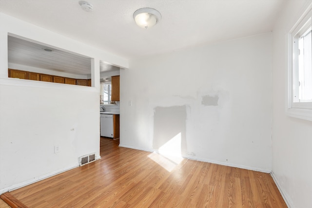 empty room with visible vents, light wood-style flooring, and baseboards