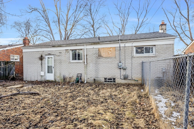 back of property with brick siding, a chimney, and fence