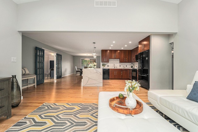 living area with light wood-style flooring, visible vents, and recessed lighting