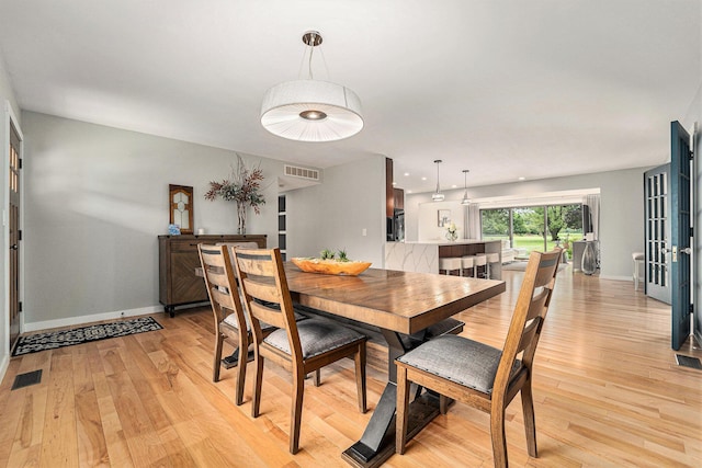 dining area featuring light wood-type flooring, baseboards, and visible vents