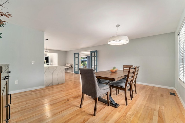 dining room with light wood-type flooring, visible vents, and baseboards