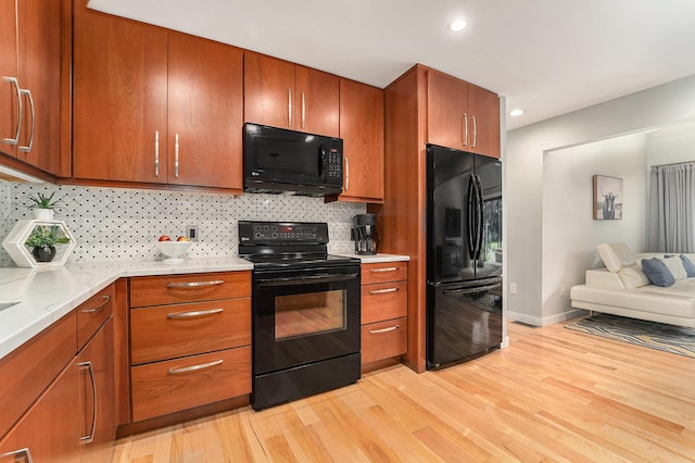 kitchen with open floor plan, light countertops, backsplash, black appliances, and light wood finished floors