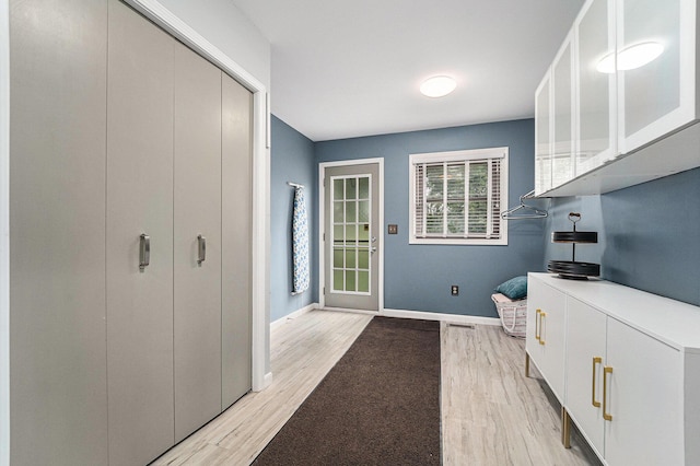 interior space featuring light countertops, light wood-type flooring, white cabinets, and baseboards