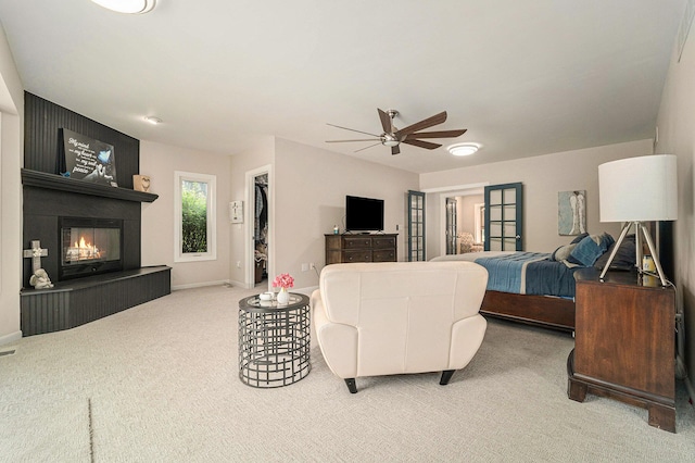 carpeted living area featuring a ceiling fan, a fireplace, and baseboards