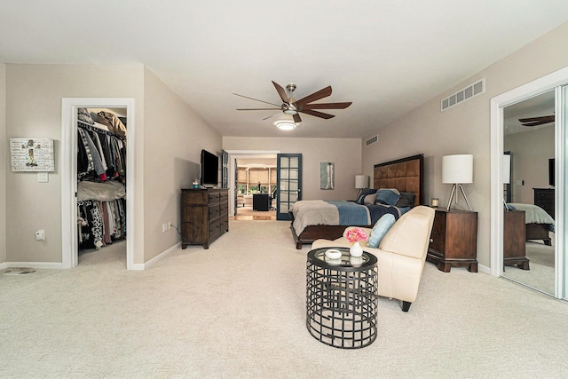 bedroom with a walk in closet, visible vents, light carpet, and baseboards