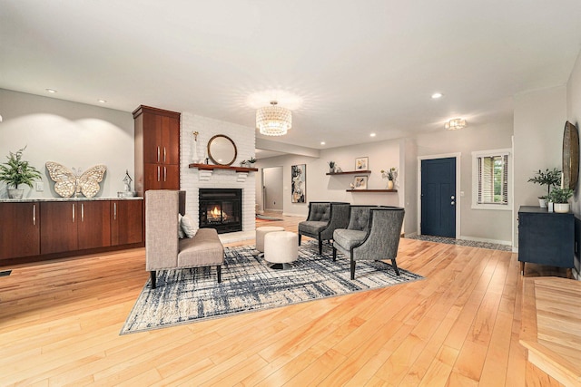 living room with a notable chandelier, recessed lighting, a fireplace, baseboards, and light wood finished floors