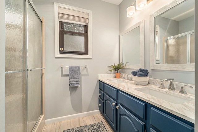 bathroom featuring a shower with door, baseboards, a sink, and wood finished floors