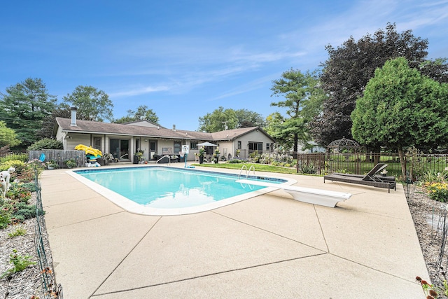 view of pool featuring a fenced in pool, a diving board, fence, and a patio