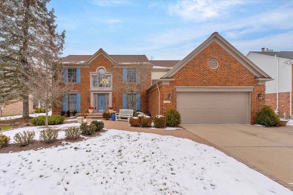 view of front of home with a garage, concrete driveway, and brick siding