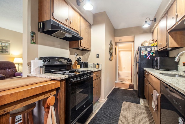 kitchen featuring black appliances, under cabinet range hood, baseboards, and a sink