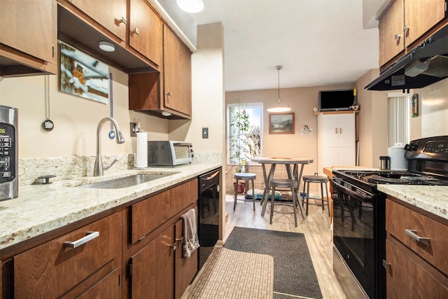 kitchen with light wood-style flooring, brown cabinets, under cabinet range hood, black appliances, and a sink