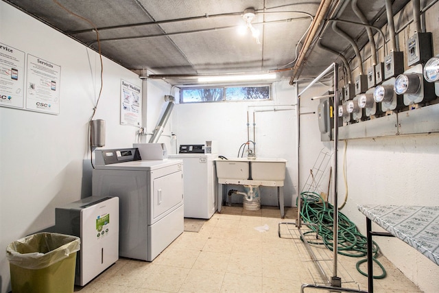 laundry room featuring washing machine and dryer, a sink, and light floors