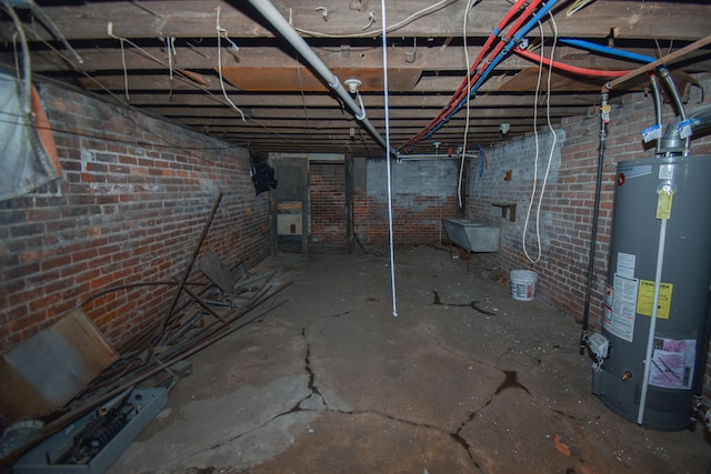 unfinished basement featuring brick wall and water heater