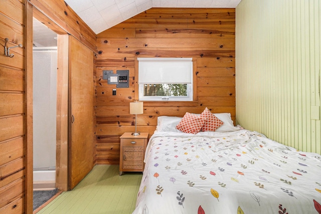 bedroom featuring lofted ceiling and wooden walls