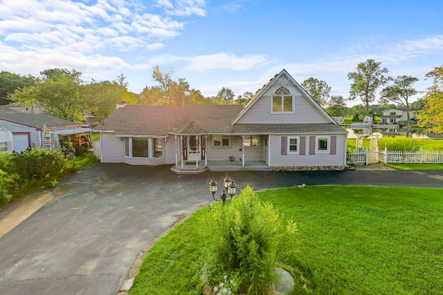 view of front of home featuring aphalt driveway, fence, and a front lawn