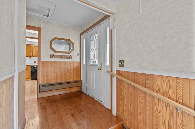 foyer entrance featuring a baseboard radiator, crown molding, and wood finished floors