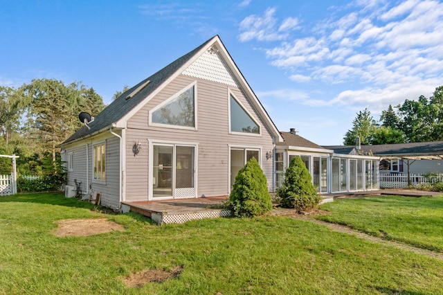 back of house with a sunroom, fence, and a lawn