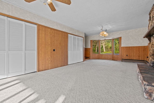 interior space featuring light carpet, a baseboard heating unit, wainscoting, and two closets