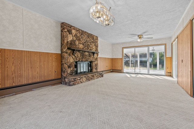 unfurnished living room featuring carpet floors, a wainscoted wall, a fireplace, and a baseboard heating unit