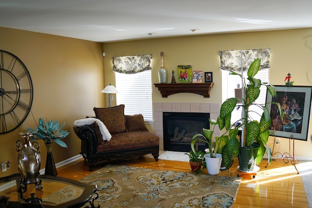 living room featuring wood finished floors, a tile fireplace, and baseboards