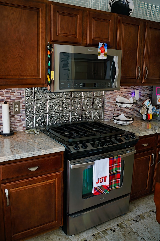 kitchen featuring appliances with stainless steel finishes, light stone counters, and decorative backsplash