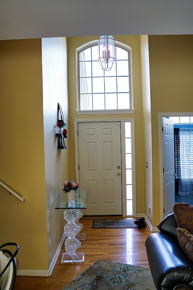 foyer with a high ceiling, wood finished floors, visible vents, and baseboards