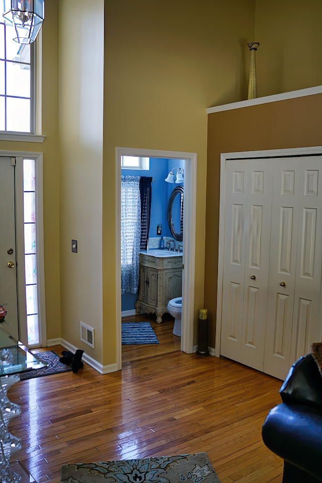 foyer entrance featuring a towering ceiling, baseboards, visible vents, and hardwood / wood-style floors