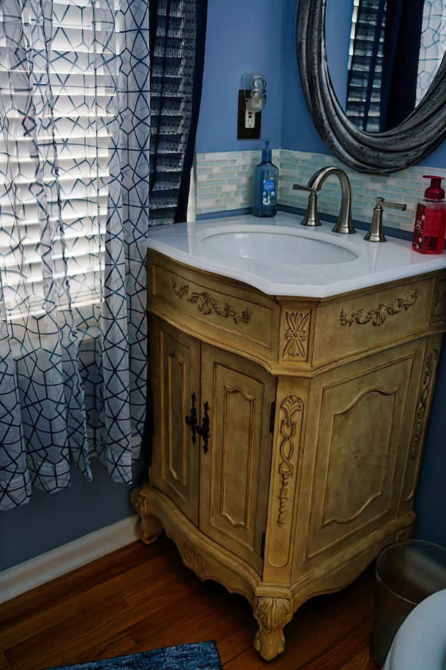 half bath featuring wood finished floors, vanity, and decorative backsplash