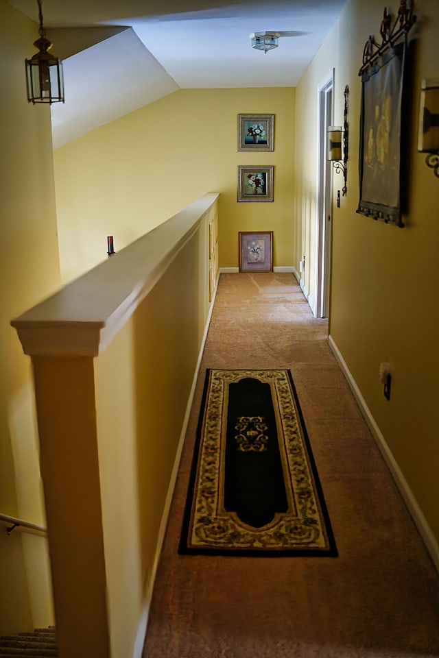 corridor with light carpet, baseboards, and lofted ceiling