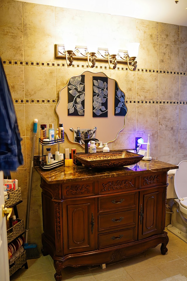 bathroom with toilet, tile patterned flooring, tile walls, and vanity