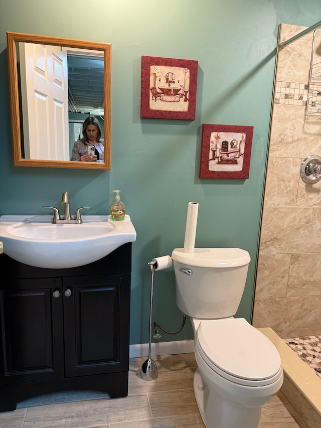 full bathroom with toilet, a shower stall, vanity, wood finished floors, and baseboards