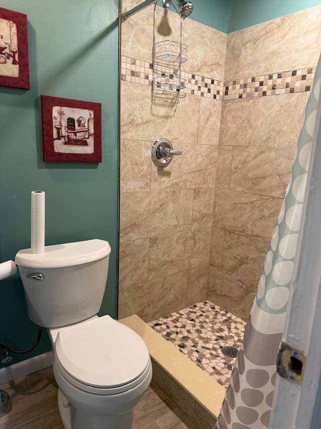 bathroom with toilet, a shower stall, baseboards, and wood finished floors