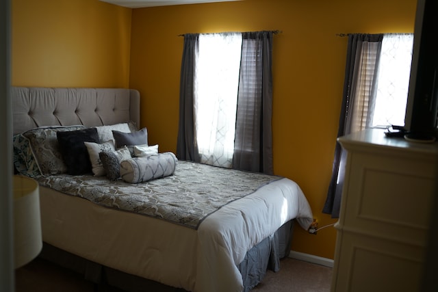 bedroom featuring carpet, multiple windows, and baseboards