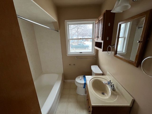 bathroom featuring toilet, vanity, baseboards, tile patterned floors, and washtub / shower combination