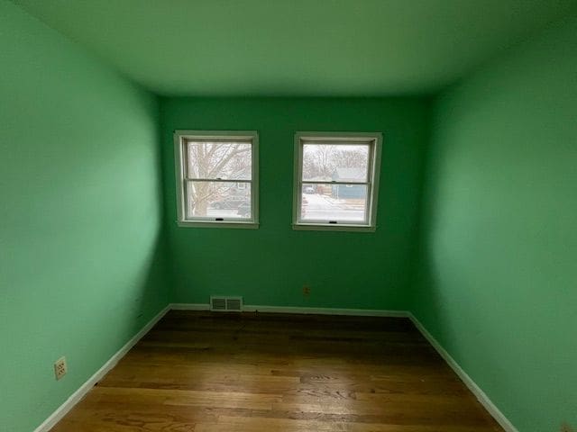 empty room with baseboards, visible vents, and wood finished floors