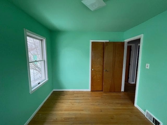 unfurnished bedroom with light wood-style floors, a closet, visible vents, and baseboards