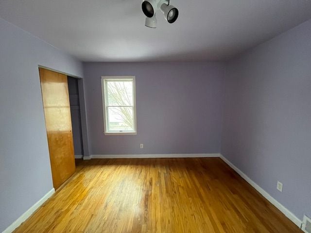 unfurnished bedroom with a closet, visible vents, light wood-style flooring, and baseboards