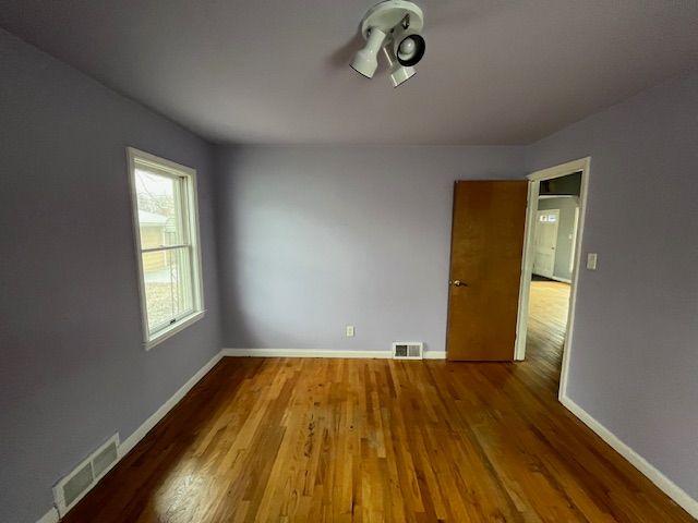 spare room with visible vents, baseboards, and wood finished floors