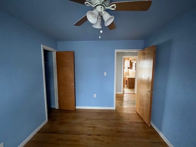 unfurnished bedroom with dark wood-style floors, ceiling fan, and baseboards