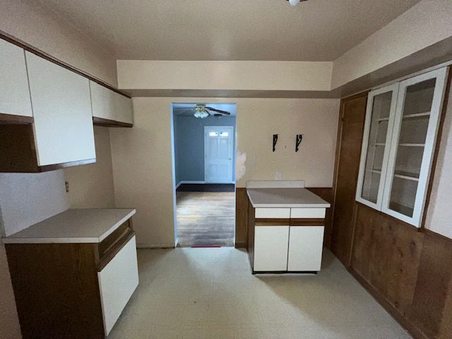 kitchen with glass insert cabinets, white cabinets, light countertops, and ceiling fan