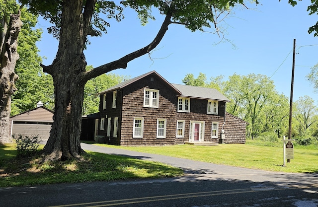 shingle-style home featuring an outbuilding, a front lawn, and a detached garage