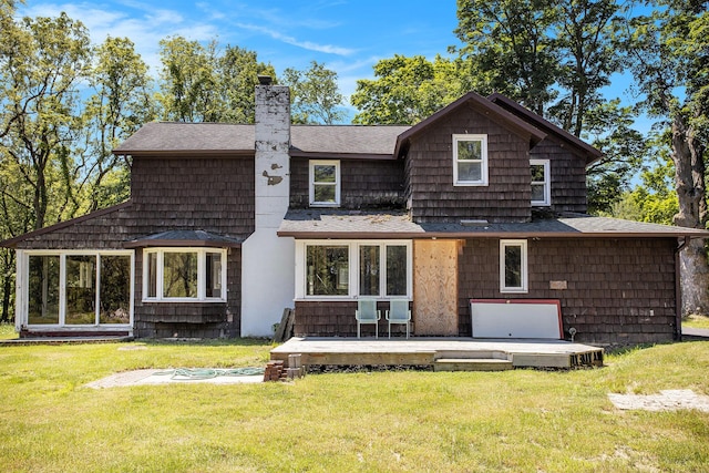 rear view of property with roof with shingles, a chimney, a deck, and a yard